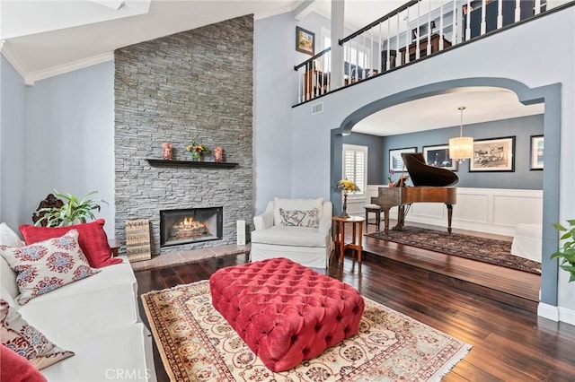 living room featuring a stone fireplace, arched walkways, hardwood / wood-style floors, and high vaulted ceiling