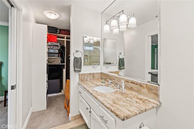 bathroom featuring a spacious closet and vanity