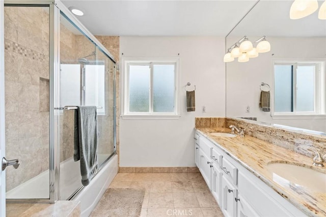 bathroom featuring shower / bath combination with glass door, double vanity, baseboards, and a sink