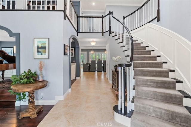 entryway with french doors, arched walkways, stairs, and crown molding
