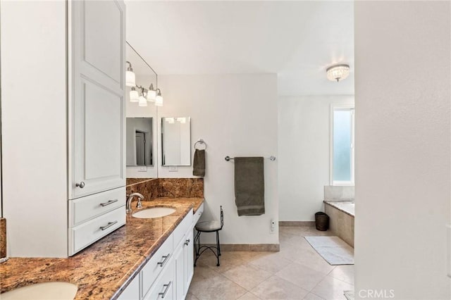 bathroom with tile patterned flooring, double vanity, a sink, a bath, and baseboards