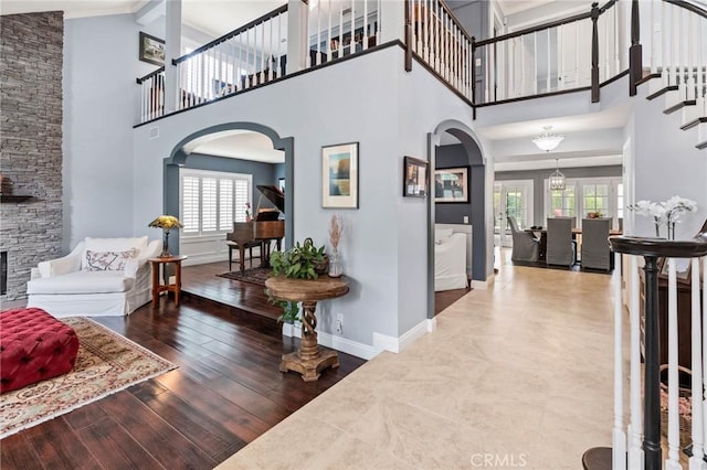entryway with arched walkways, a high ceiling, baseboards, and a fireplace