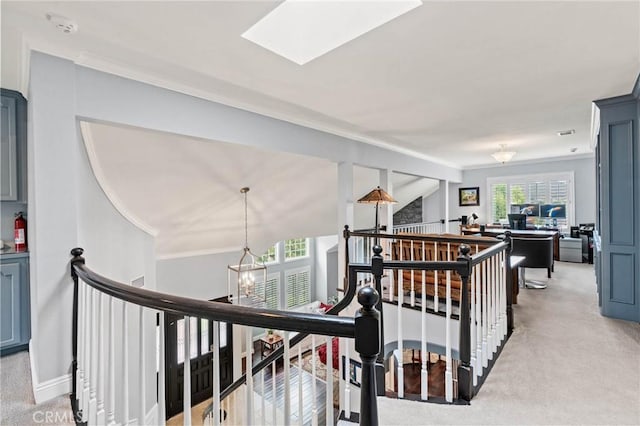 hallway featuring light carpet, baseboards, an inviting chandelier, an upstairs landing, and crown molding