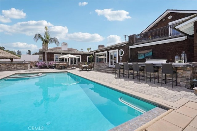 pool featuring outdoor dry bar, a patio, and an in ground hot tub