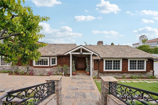 ranch-style house with a chimney, a front lawn, and stone siding