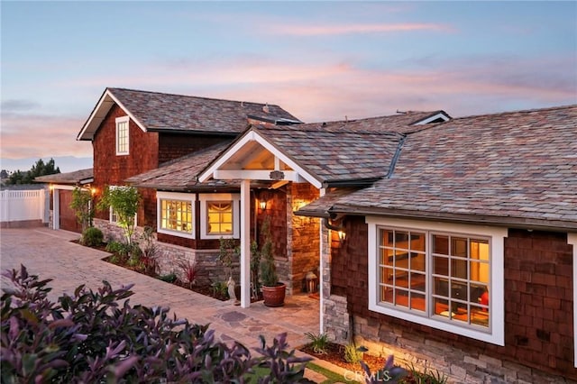 view of front of house with driveway, fence, and stone siding