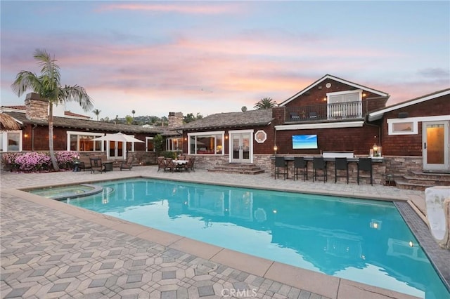 view of pool featuring french doors, outdoor dry bar, entry steps, a patio area, and a pool with connected hot tub