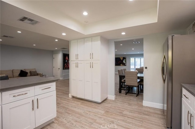 73640 Joshua Tree St, Palm Desert, CA 92260 - kitchen with white cabinets, light wood-style flooring, dark countertops, visible vents, and freestanding refrigerator