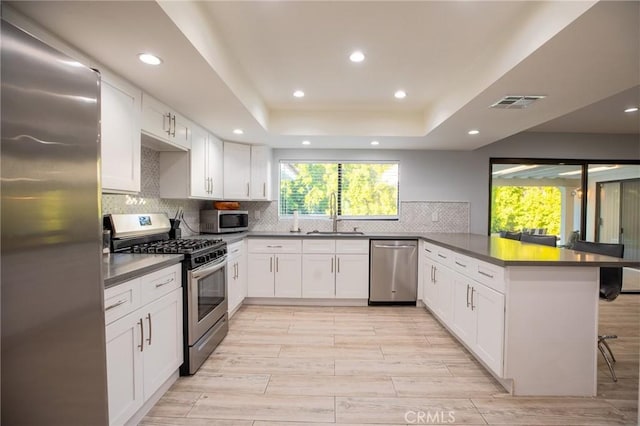 73640 Joshua Tree St, Palm Desert, CA 92260 - kitchen featuring dark countertops, tasteful backsplash, a peninsula, appliances with stainless steel finishes, and visible vents