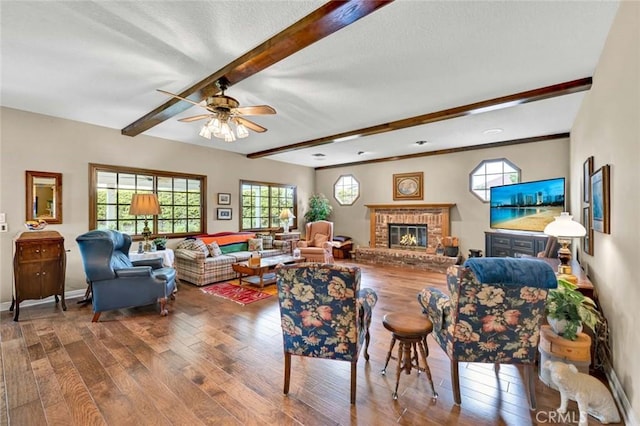 living area with beamed ceiling, ceiling fan, a wealth of natural light, and wood finished floors