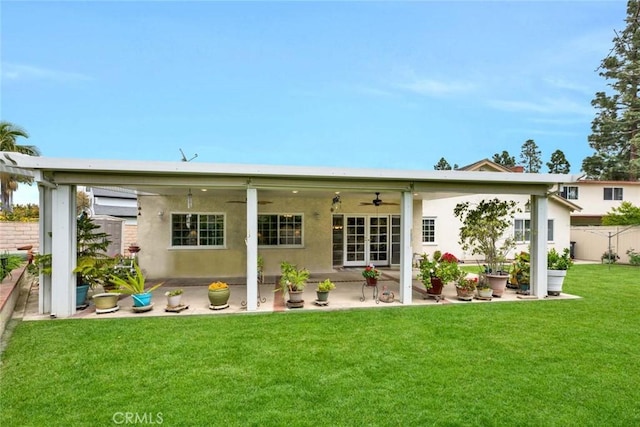 rear view of property featuring a patio, stucco siding, a yard, fence, and a ceiling fan