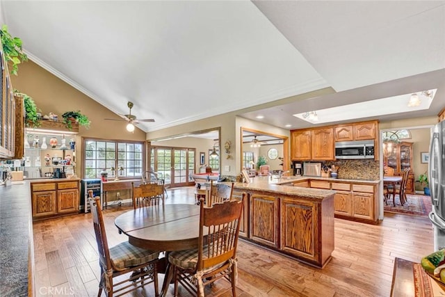 dining area featuring ornamental molding, ceiling fan, high vaulted ceiling, and light wood-style floors