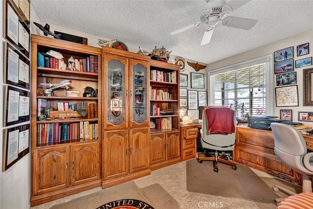 home office featuring a textured ceiling, ceiling fan, and light colored carpet