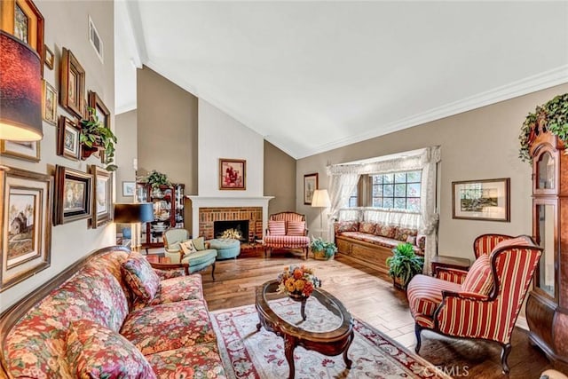 living area featuring lofted ceiling, crown molding, visible vents, a fireplace, and wood finished floors