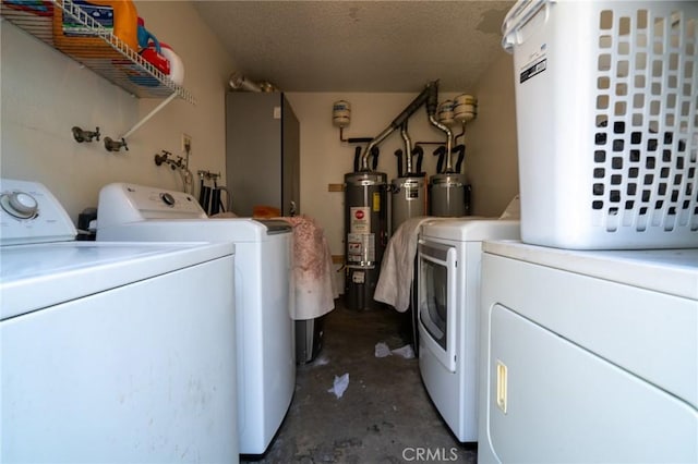 laundry room with washing machine and dryer, water heater, a textured ceiling, and laundry area