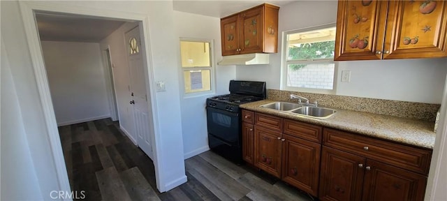 kitchen with a sink, dark wood finished floors, gas stove, light countertops, and under cabinet range hood