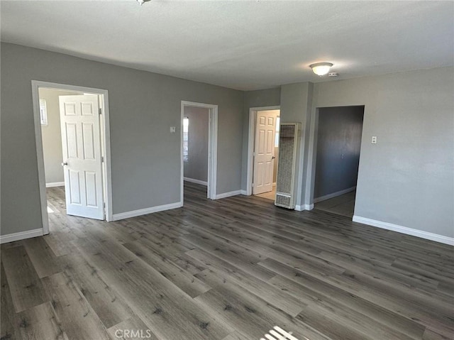 spare room featuring dark wood finished floors and baseboards