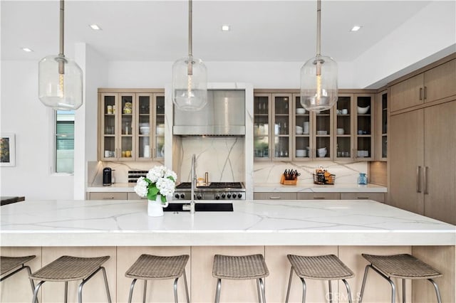 429 Marigold Ave, Corona Del Mar, CA 92625 - kitchen with glass insert cabinets, light stone countertops, decorative light fixtures, wall chimney range hood, and tasteful backsplash