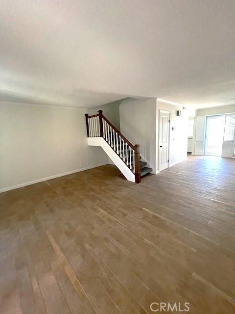 unfurnished room with stairs, wood finished floors, and baseboards