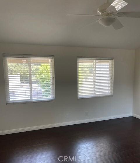 unfurnished room with dark wood-type flooring, ceiling fan, and baseboards
