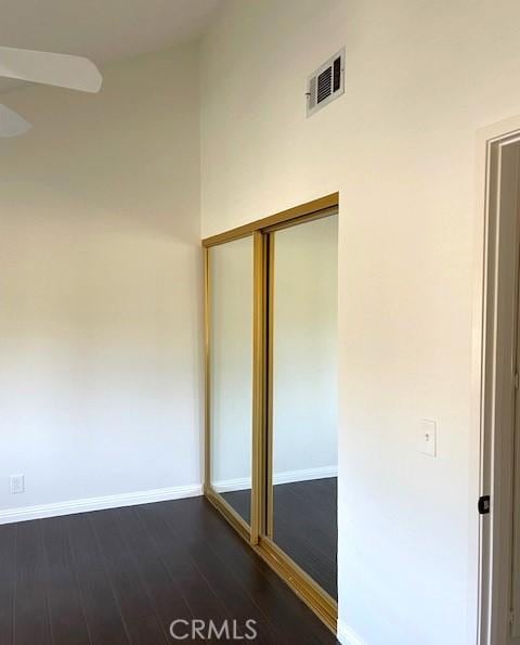 spare room featuring ceiling fan, dark wood-style flooring, and baseboards