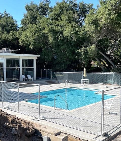 community pool featuring a patio area and view of wooded area