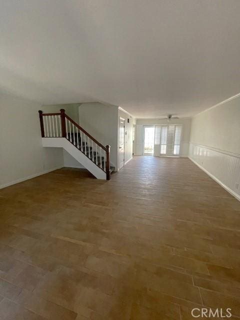 empty room with baseboards, wood finished floors, and stairway