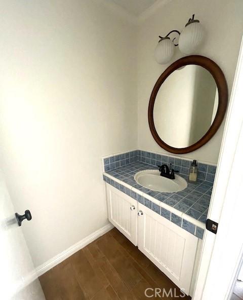 bathroom with wood finished floors, vanity, and baseboards