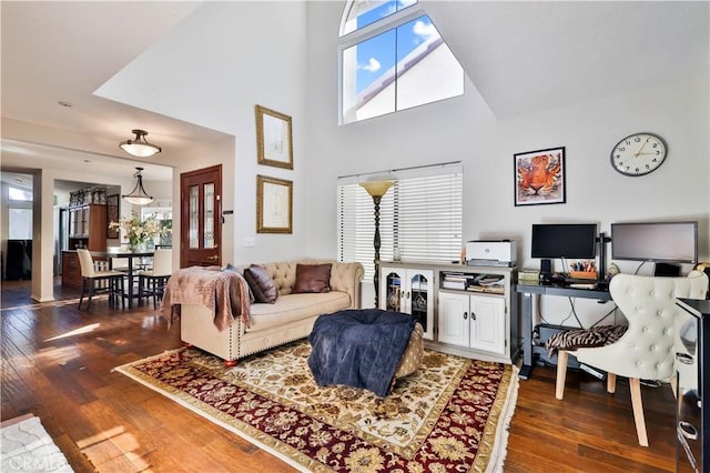 living area featuring a wealth of natural light, hardwood / wood-style flooring, and a towering ceiling