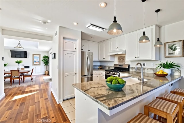 3014 Enrique Unit 98, San Clemente, CA 92673 - kitchen with appliances with stainless steel finishes, a sink, a peninsula, white cabinetry, and dark stone countertops