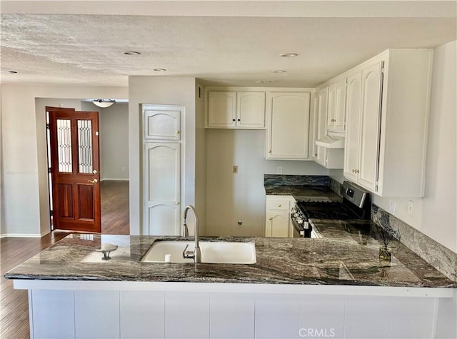 3014 Enrique Unit 98, San Clemente, CA 92673 - kitchen with gas stove, dark stone countertops, under cabinet range hood, a peninsula, and a textured ceiling