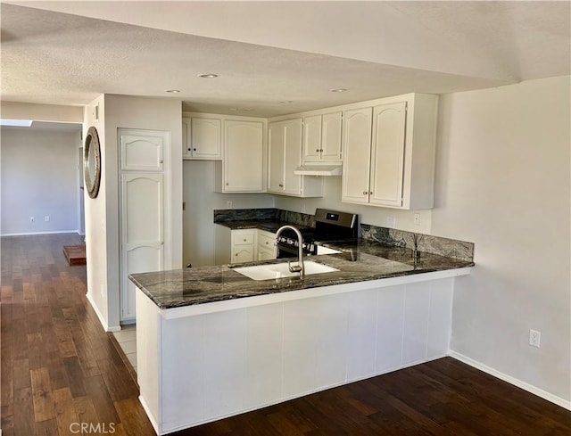 3014 Enrique Unit 98, San Clemente, CA 92673 - kitchen featuring dark stone countertops, a peninsula, electric stove, dark wood-style flooring, and recessed lighting