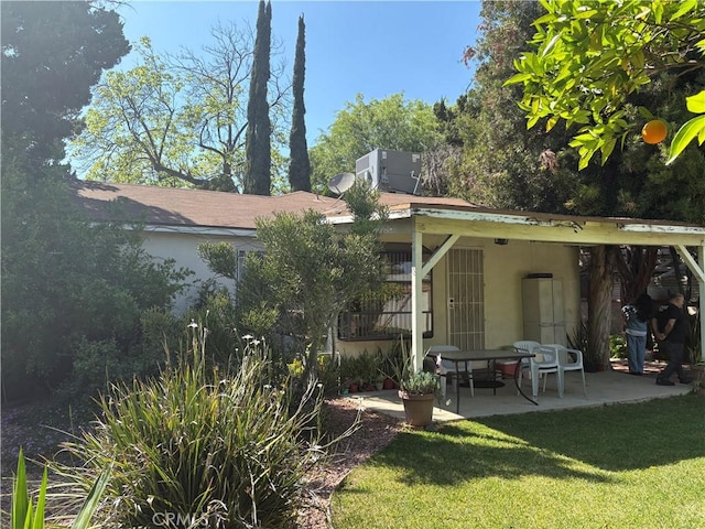 back of house featuring a lawn, stucco siding, and a patio area