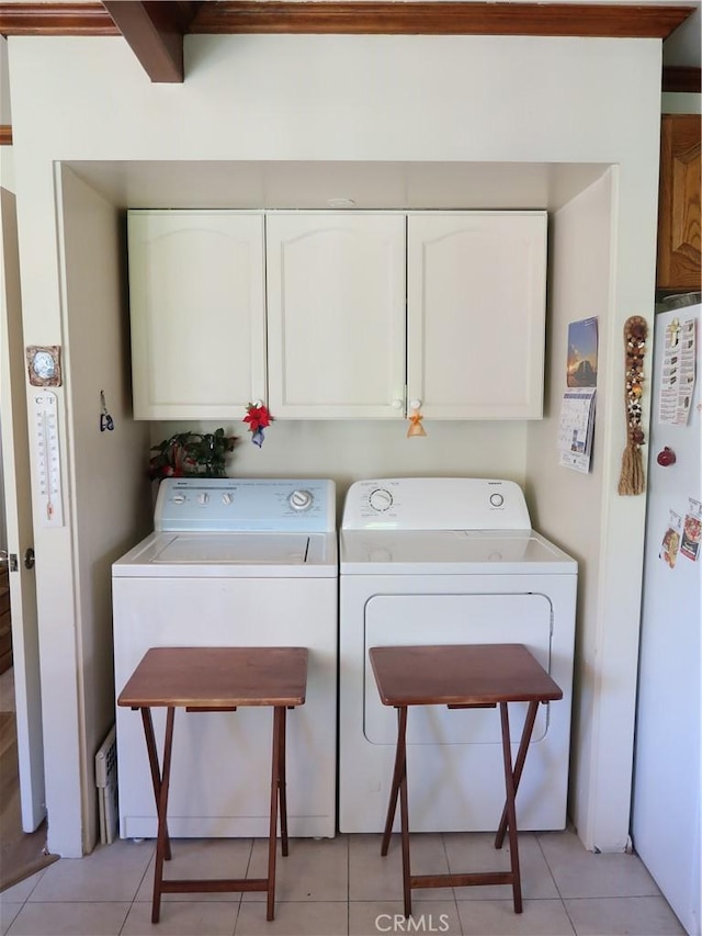 washroom with light tile patterned flooring, cabinet space, and washing machine and dryer