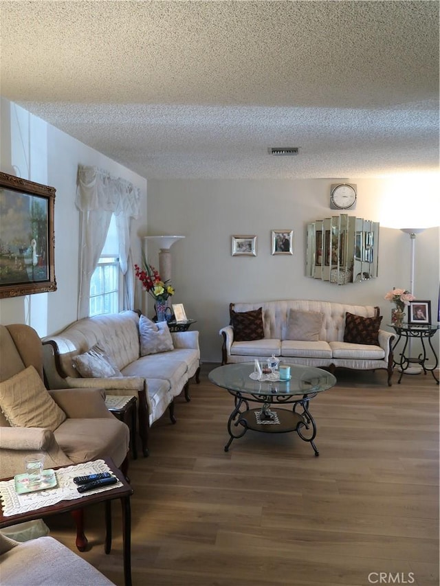 living area featuring a textured ceiling, visible vents, and wood finished floors