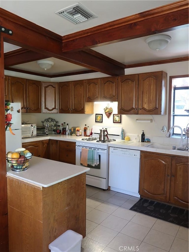 kitchen featuring a sink, beam ceiling, white appliances, visible vents, and light countertops
