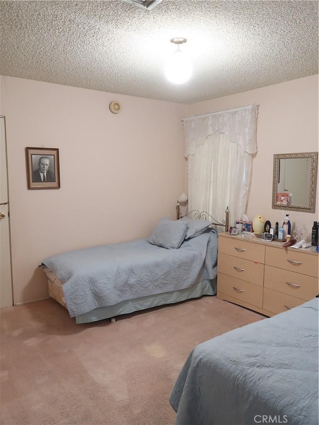 bedroom featuring a textured ceiling and light colored carpet