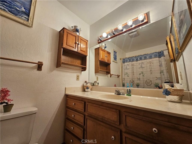 bathroom with curtained shower, toilet, and vanity