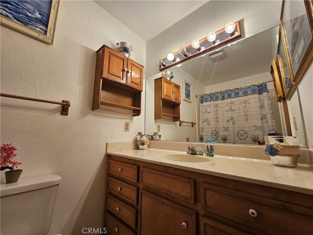 bathroom featuring a textured wall, vanity, curtained shower, and toilet