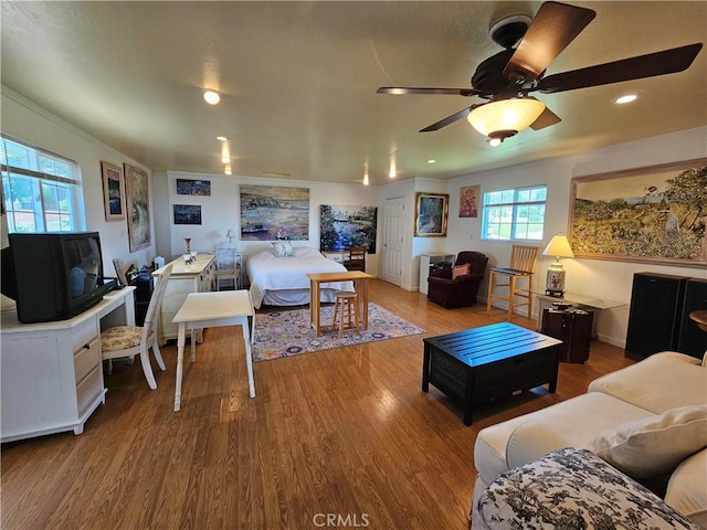 living area with recessed lighting, wood finished floors, ceiling fan, and ornamental molding