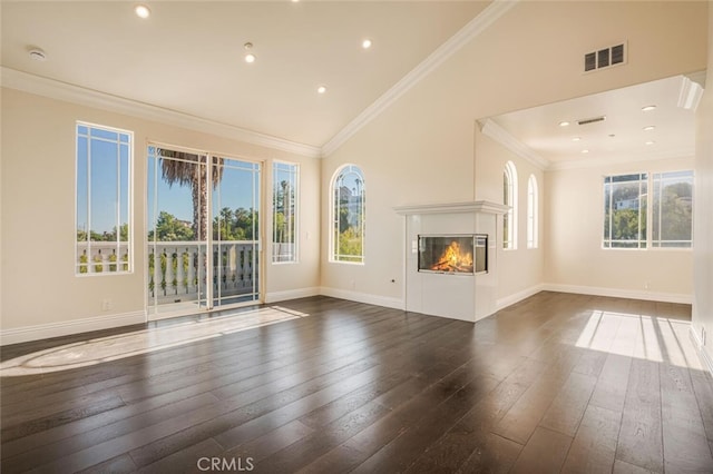 unfurnished living room featuring dark wood-type flooring, a glass covered fireplace, baseboards, ornamental molding, and high vaulted ceiling