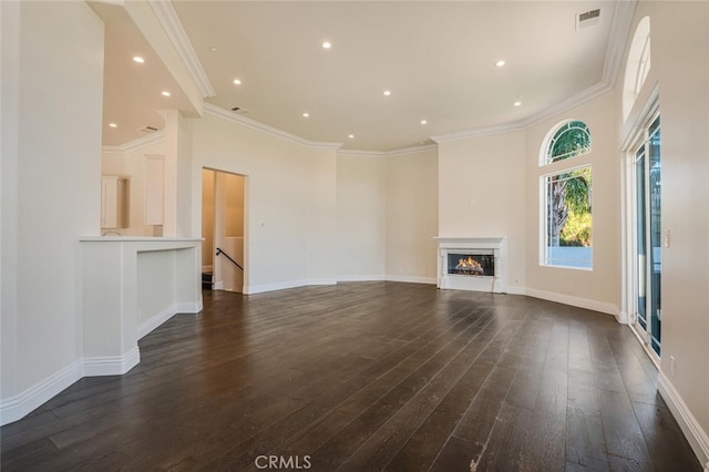 unfurnished living room featuring dark wood finished floors, ornamental molding, a lit fireplace, recessed lighting, and baseboards