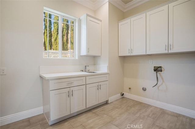 clothes washing area featuring gas dryer hookup, cabinet space, baseboards, crown molding, and washer hookup