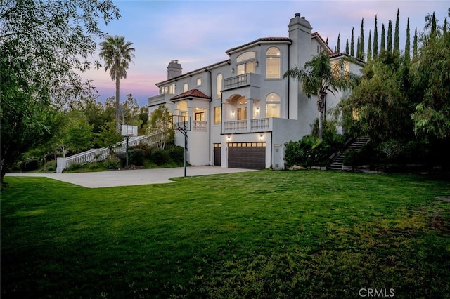 mediterranean / spanish house with a balcony, a chimney, stairs, a garage, and stucco siding