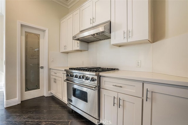 kitchen featuring premium range, under cabinet range hood, light countertops, crown molding, and white cabinets