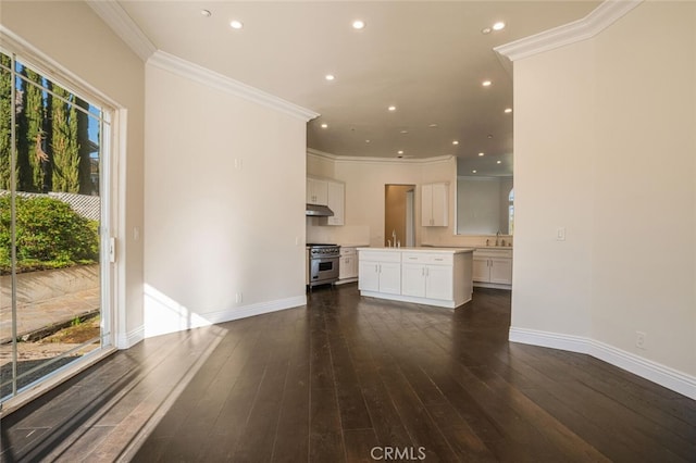 unfurnished living room featuring crown molding, recessed lighting, baseboards, dark wood-style floors, and a sink