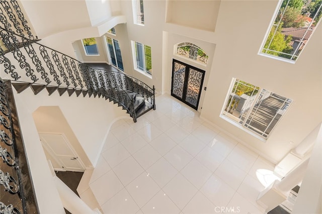 tiled entryway with a high ceiling and stairway