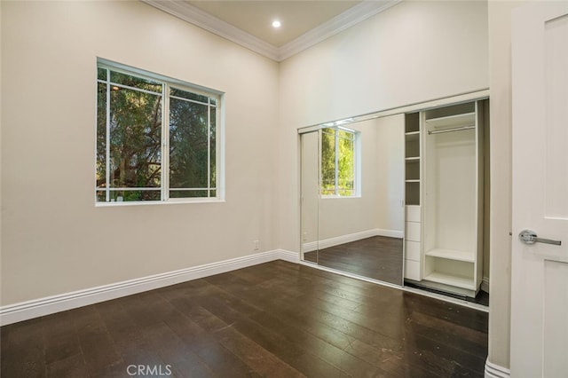 unfurnished bedroom with ornamental molding, hardwood / wood-style floors, baseboards, and a closet
