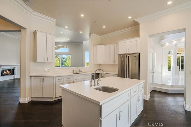 kitchen featuring a sink, high quality fridge, white cabinetry, light countertops, and crown molding