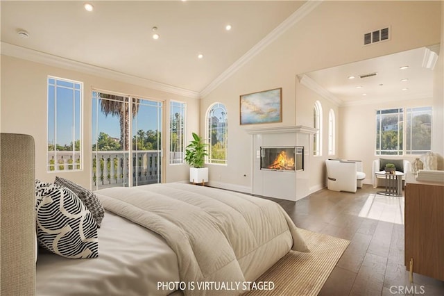 bedroom featuring dark wood-style floors, a glass covered fireplace, ornamental molding, baseboards, and recessed lighting